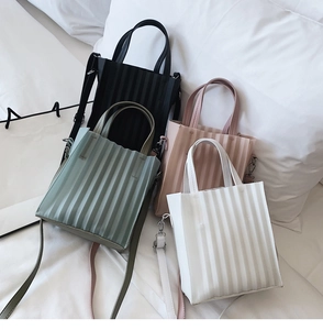 Détail de sacs fourre-tout plissés en noir, vert, rose et blanc avec bandoulières réglables