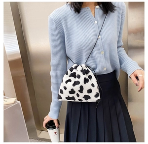 Detail of plush cow print crossbody bag with drawstring closure and slim shoulder strap