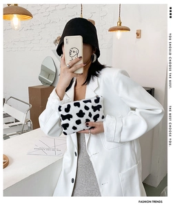 Détail de la texture en peluche à motif vache noir et blanc avec fermeture éclair en métal