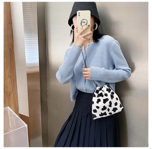 Detail view of the black and white cow print drawstring bucket bag with winter outfit