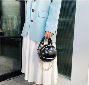 Détail du sac de basket en cuir noir avec chaînes dorées et texte imprimé élégant
