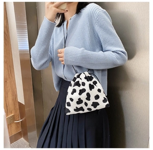 Close-up of fluffy black and white cow print plush handbag with drawstring closure