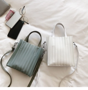 Détail des sacs à bandoulière plissés en vert sauge et blanc avec des ferrures argentées