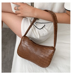 Détail d'un sac baguette marron à motif crocodile avec fermeture éclair et bandoulière