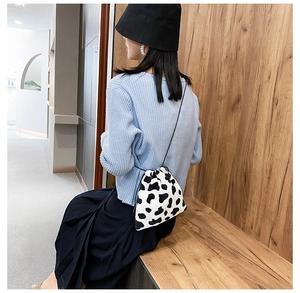 Detail of a mini cow print bucket bag with drawstring closure and slim shoulder strap
