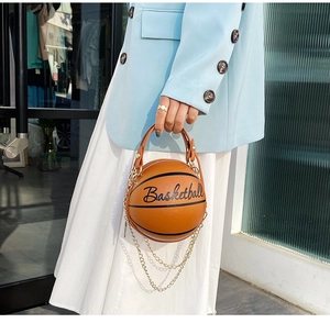 Detalle del bolso bandolera naranja con forma de baloncesto y cadena dorada elegante