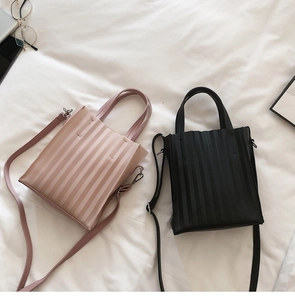 Détail de mini sacs cabas plissés en rose et noir sur un lit blanc moelleux