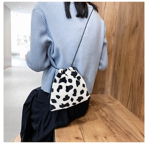 Detail of soft black and white cow print plush bucket bag with a thin shoulder strap