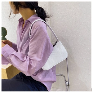 Vue détaillée du sac baguette blanc à motif crocodile porté à l'épaule par le mannequin