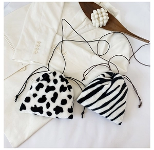 Detail of plush faux fur drawstring pouches in cow and zebra prints on a soft white blazer