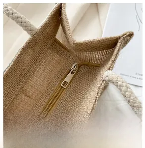 Close-up of durable zipper closure and woven handles on beige canvas tote bag