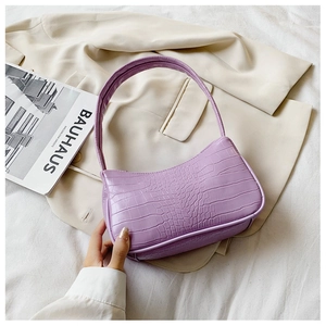 Détail du sac porté épaule violet à motif crocodile sur un blazer beige élégant