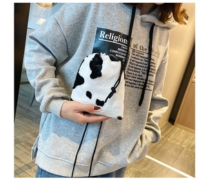 Detail of soft faux fur bucket bag with black and white cow print and drawstring closure