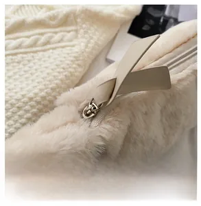 Detailed macro view of smooth silver zipper on fluffy beige plush shoulder bag fabric