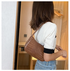 Sac baguette marron à motif crocodile porté par un modèle au style rétro chic