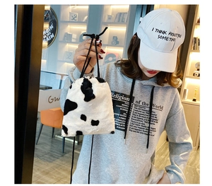 Detailed close-up of soft cow print plush bucket bag with elegant black drawstring closure