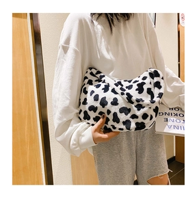 Vista dettagliata di una borsa a spalla in peluche con stampa mucca indossata da modella