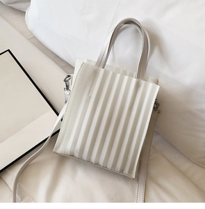 Détail d'un sac à main plissé blanc avec plis verticaux et bandoulière minimaliste