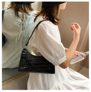 Mirror reflection showing a black crocodile pattern baguette underarm bag with glossy finish