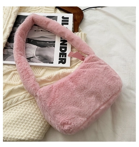 Detailed close-up of a pink faux fur shoulder bag resting on a white knitted sweater