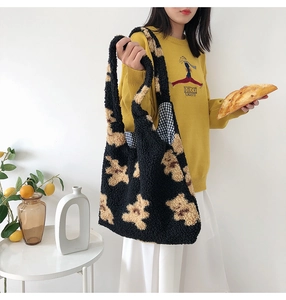 Detail of plush black tote bag featuring brown bear jacquard and blue checkered lining