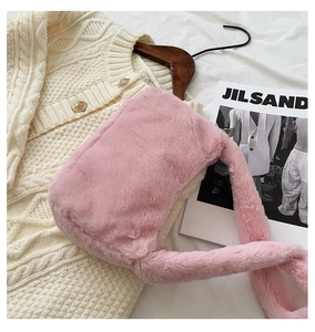 Close-up of pink plush underarm bag with soft faux fur texture on knitted cardigan