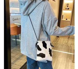 Close-up of small faux fur cow print bucket bag with drawstring and shoulder strap
