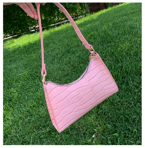 Detailed close-up of pink faux-croc texture and metal zipper on this stylish baguette bag