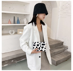Porte-monnaie tendance en peluche motif vache tenu par un mannequin en décor moderne