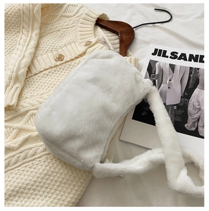 Detailed texture of white faux fur shoulder bag styled on a knit sweater background