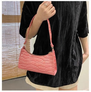 Detail of pink crocodile embossed faux leather baguette bag with gold metal zipper