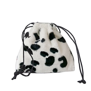 White faux fur drawstring bag with black cow print pattern and secure toggle closure