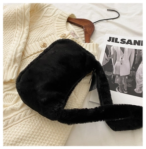 Close-up of black faux fur shoulder bag on a white knit sweater with a cozy winter vibe