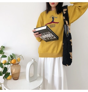 Detail of cute fluffy black bear tote bag paired with yellow knitted sweater in Seoul style