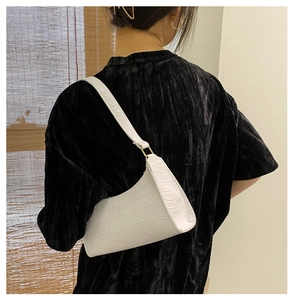 Detailed close-up of white crocodile pattern faux leather texture on underarm bag