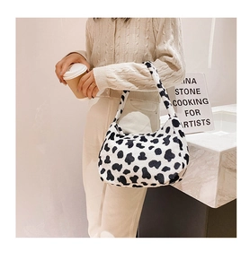 Dettaglio della borsa sottobraccio in peluche muccata con cardigan in maglia beige