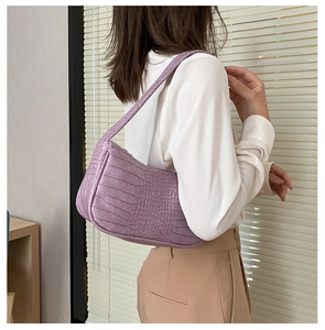 Vue détaillée du sac baguette lilas avec motif crocodile porté à l'épaule de côté