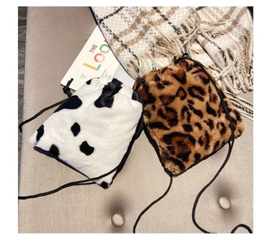 Detail of plush faux fur drawstring bags in cow and leopard prints for autumn winter