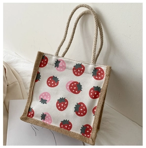 Detail of strawberry print canvas tote bag with woven jute handles and trim detail