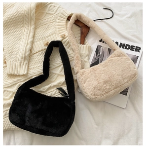 Detail of plush faux fur shoulder bags in black and beige resting on knit fabric