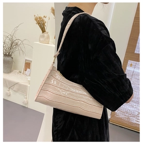 Detail view of pink crocodile pattern underarm bag with glossy patent leather texture