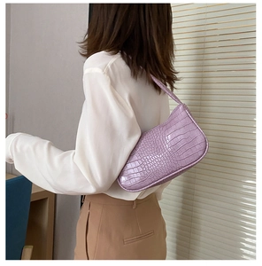 Détail du sac baguette lavande avec motif crocodile et finition en cuir texturé