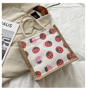 Detail of canvas strawberry tote bag featuring natural jute sides and thick cotton rope handles