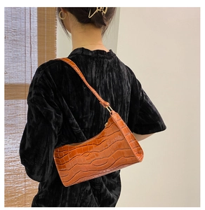 Deep orange crocodile pattern shoulder bag on model with elegant gold hardware
