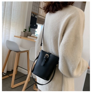 Chic black leather bucket bag shown on model in cozy interior setting with gold hardware