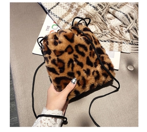 Close-up of leopard print faux fur bucket bag with black drawstring and fluffy texture