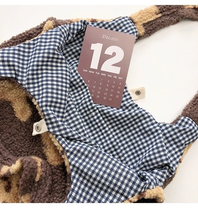 Detail of plush tote bag showing blue plaid lining and silver magnetic snap button