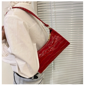 Detailed close-up of a red crocodile pattern shoulder bag with golden zipper hardware