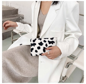 Gros plan d'un porte-monnaie en fausse fourrure à motif vache tenu par un mannequin
