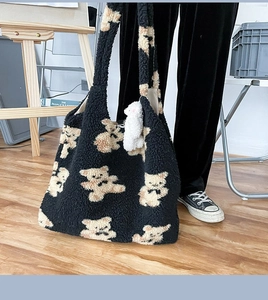 Dettaglio della borsa tote in pile nero con motivo di orsetti e ciondolo di peluche